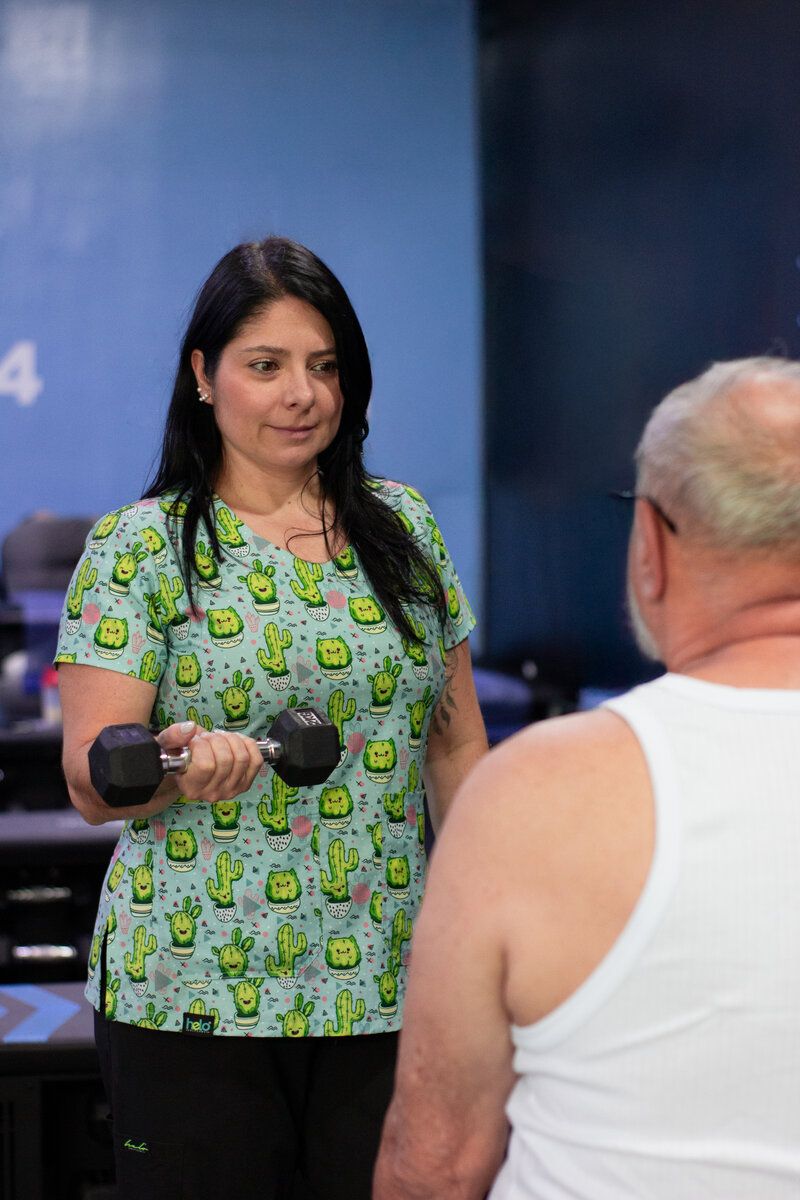 Raquel Mejía demonstrating dumbbell exercises with a patient during a physical therapy session