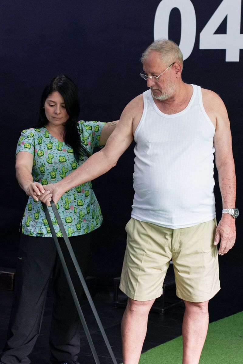 Patient performing standing resistance band exercises guided by Raquel Mejía